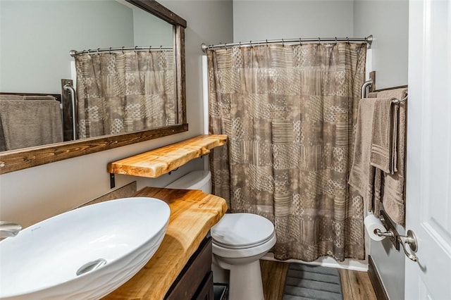 bathroom with hardwood / wood-style flooring, vanity, curtained shower, and toilet