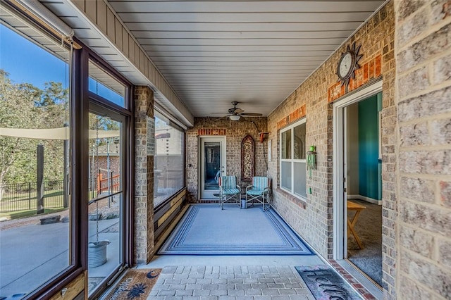 unfurnished sunroom featuring ceiling fan and plenty of natural light