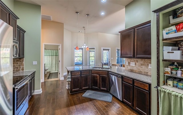 kitchen with stainless steel appliances, light stone counters, hanging light fixtures, and dark hardwood / wood-style floors