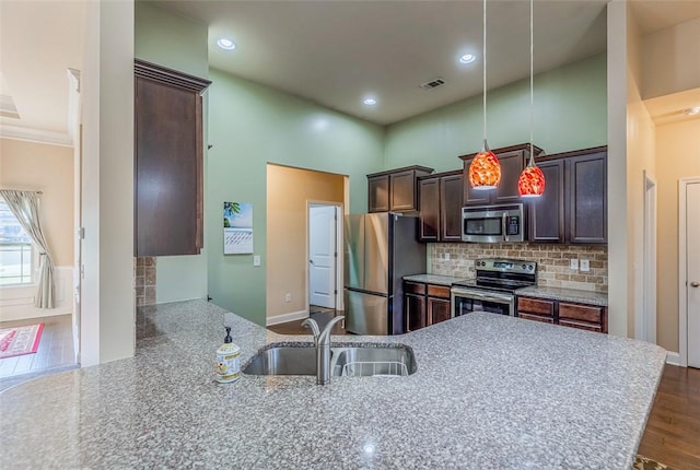 kitchen with backsplash, stainless steel appliances, dark wood-type flooring, sink, and pendant lighting