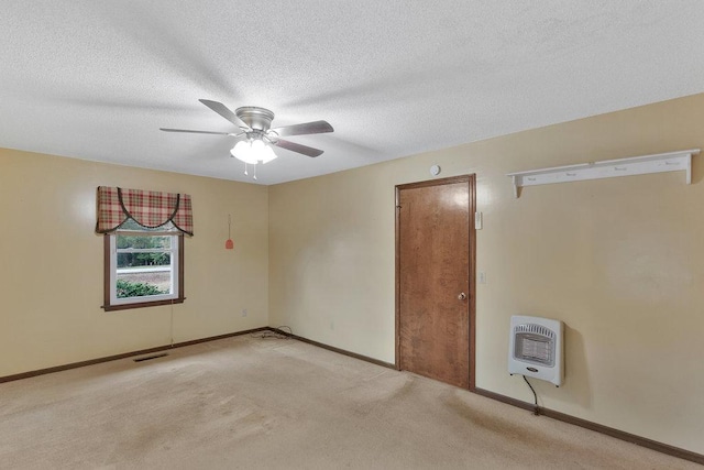 empty room featuring light carpet, a textured ceiling, heating unit, and ceiling fan