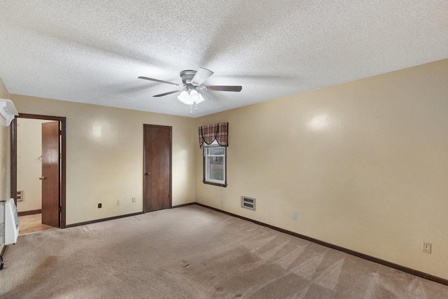 unfurnished bedroom with ceiling fan, light colored carpet, and a textured ceiling