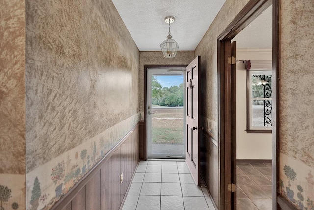 doorway to outside with a textured ceiling and light tile patterned flooring