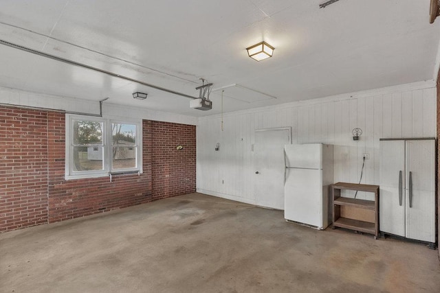 garage with wood walls, white refrigerator, and a garage door opener