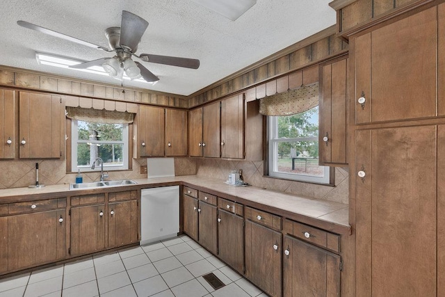 kitchen featuring backsplash, dishwasher, a healthy amount of sunlight, and sink