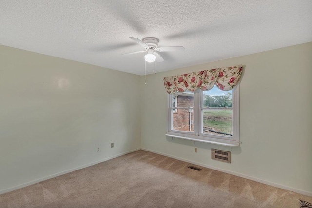 spare room featuring light carpet, a textured ceiling, and ceiling fan