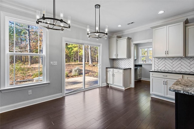 kitchen featuring pendant lighting, a healthy amount of sunlight, dark hardwood / wood-style floors, and a notable chandelier