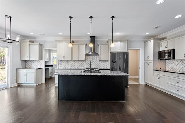 kitchen featuring pendant lighting, a kitchen island with sink, wall chimney exhaust hood, and appliances with stainless steel finishes