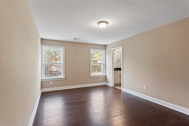 spare room with dark wood-type flooring and a wealth of natural light