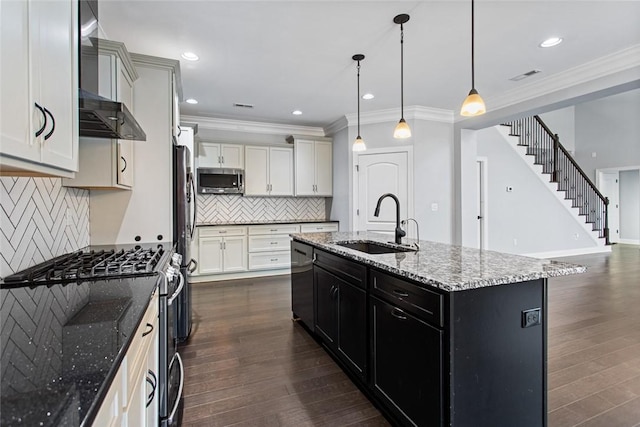 kitchen with sink, dark wood-type flooring, pendant lighting, a kitchen island with sink, and appliances with stainless steel finishes