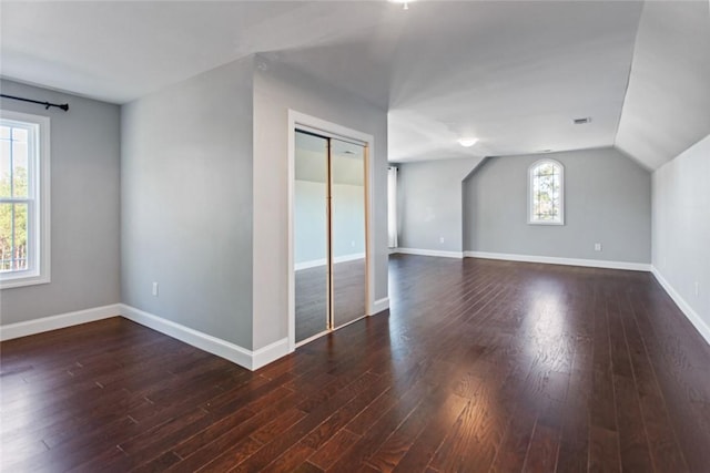 bonus room featuring plenty of natural light, dark wood-type flooring, and vaulted ceiling