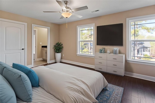 bedroom featuring connected bathroom, dark hardwood / wood-style flooring, multiple windows, and ceiling fan