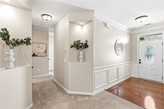 entryway with ornamental molding and light carpet