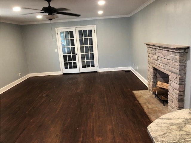 unfurnished living room featuring hardwood / wood-style floors, french doors, a stone fireplace, crown molding, and ceiling fan