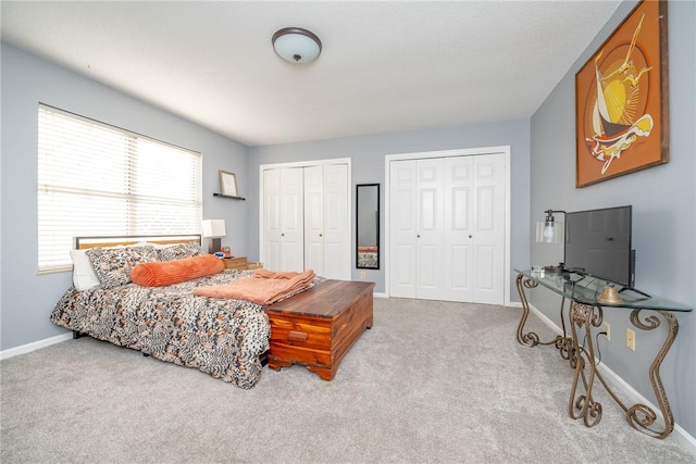 bedroom with light carpet and two closets