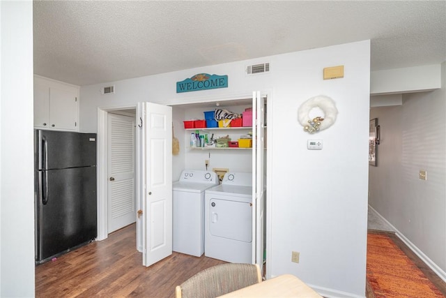 clothes washing area featuring washer and dryer, a textured ceiling, and wood-type flooring