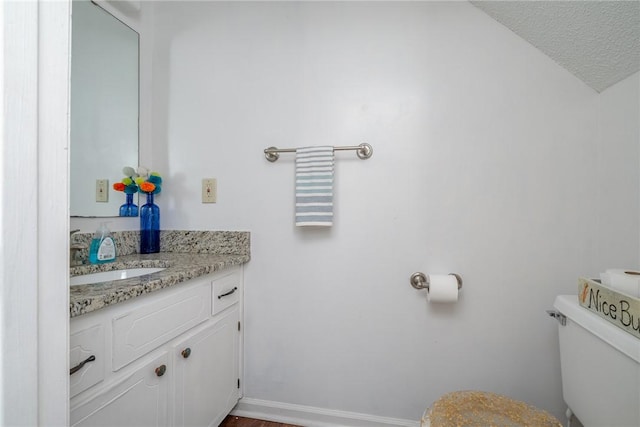 bathroom with vanity, toilet, and a textured ceiling