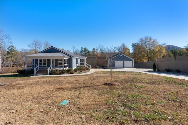 ranch-style home featuring covered porch, an outbuilding, a garage, and a front yard