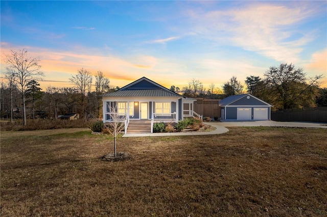 ranch-style home featuring a porch, a garage, an outdoor structure, and a lawn