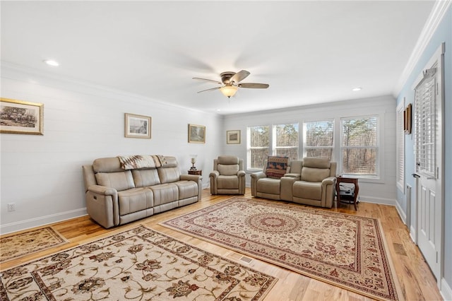 living room with ceiling fan, ornamental molding, and light wood-type flooring