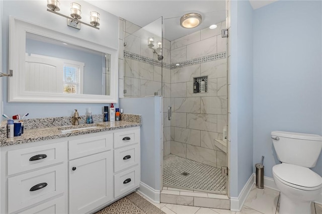 bathroom featuring vanity, a shower with shower door, and toilet