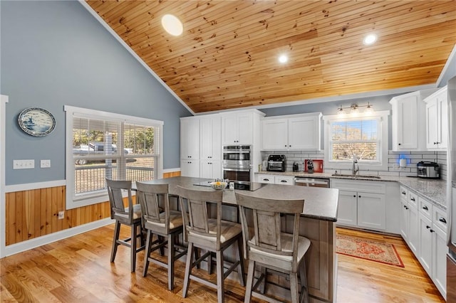 kitchen with white cabinetry, sink, a kitchen island, and light wood-type flooring