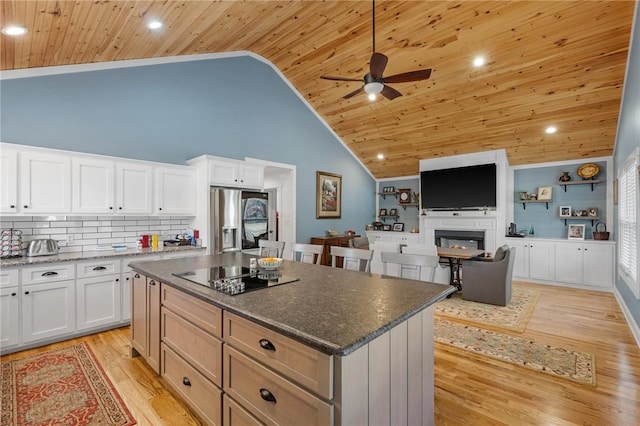 kitchen with stainless steel fridge, a kitchen island, ceiling fan, high vaulted ceiling, and white cabinetry