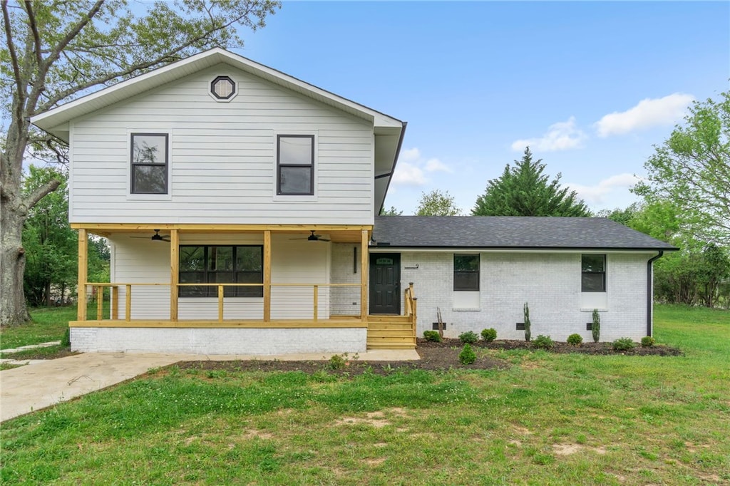 view of front of property featuring ceiling fan, a front lawn, and covered porch