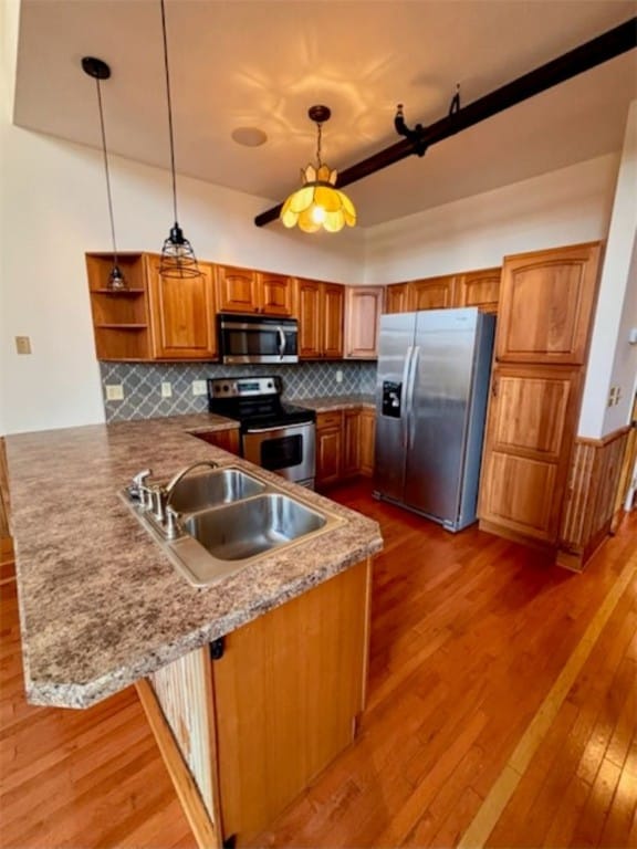 kitchen featuring kitchen peninsula, appliances with stainless steel finishes, hanging light fixtures, and sink