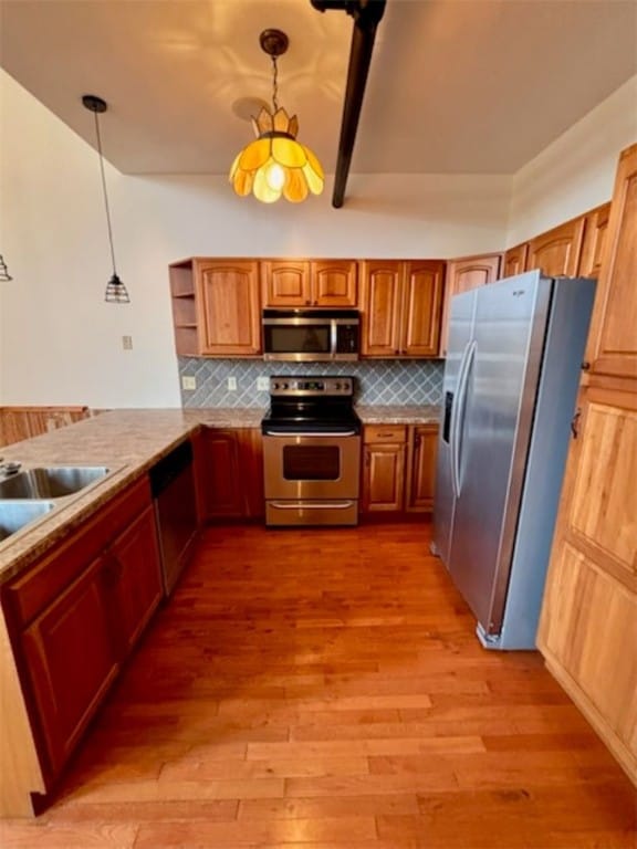 kitchen with light wood-type flooring, decorative light fixtures, and appliances with stainless steel finishes