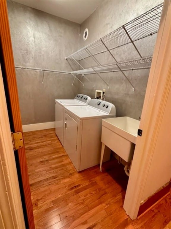 laundry area featuring light wood-type flooring, washing machine and dryer, and sink