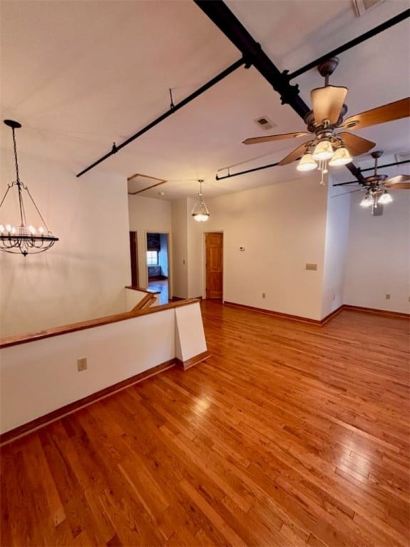 unfurnished room featuring wood-type flooring and ceiling fan with notable chandelier