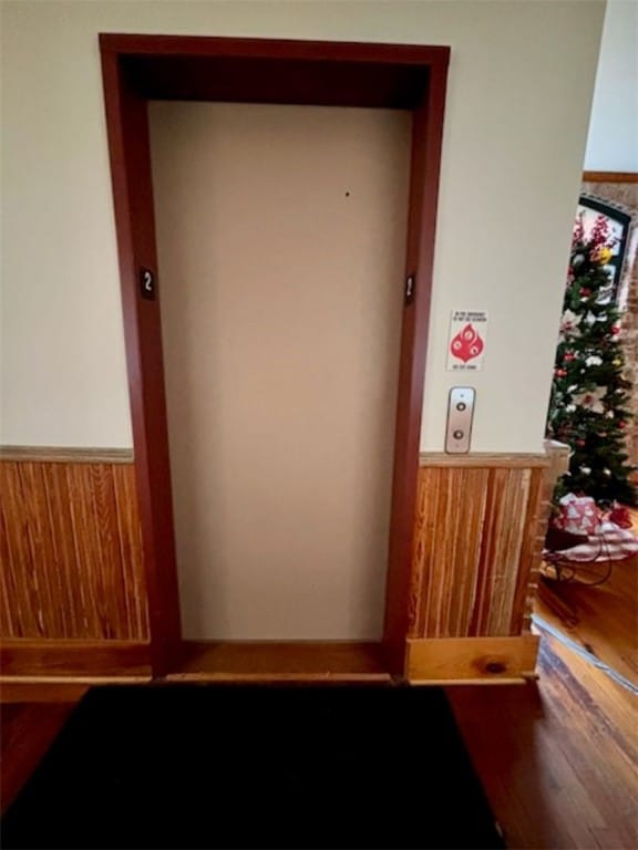 interior details with elevator and hardwood / wood-style flooring