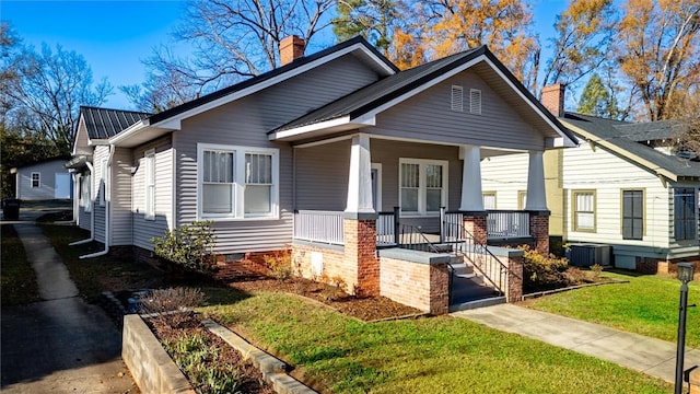 bungalow-style home with a front yard, a porch, and central AC