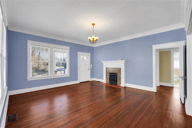 unfurnished living room with dark hardwood / wood-style flooring, an inviting chandelier, ornamental molding, and a premium fireplace