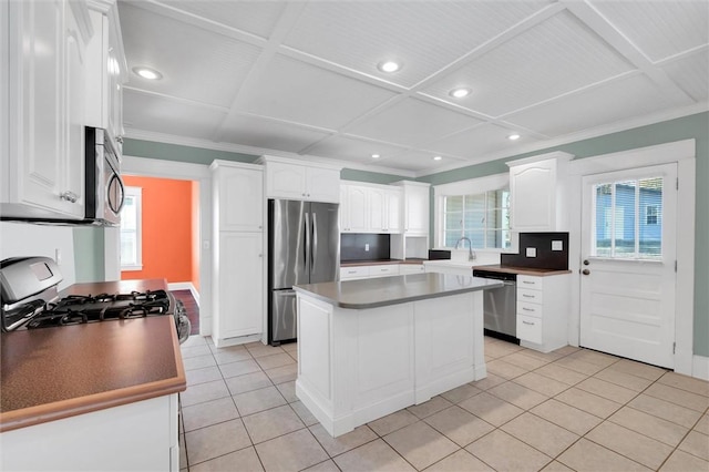 kitchen with a wealth of natural light, a center island, white cabinetry, and appliances with stainless steel finishes