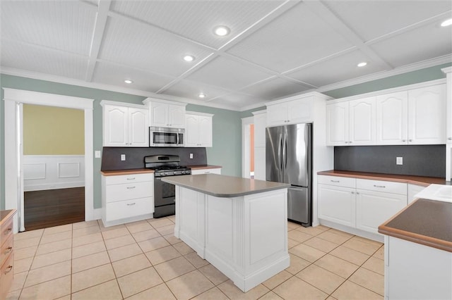 kitchen featuring coffered ceiling, stainless steel appliances, light tile patterned floors, white cabinets, and a center island