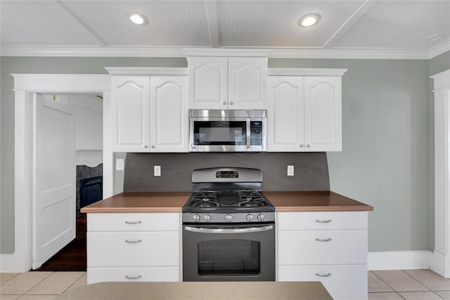 kitchen with white cabinetry, stainless steel appliances, decorative backsplash, light tile patterned floors, and ornamental molding