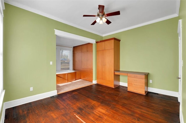 unfurnished bedroom featuring ceiling fan, dark hardwood / wood-style flooring, built in desk, and crown molding