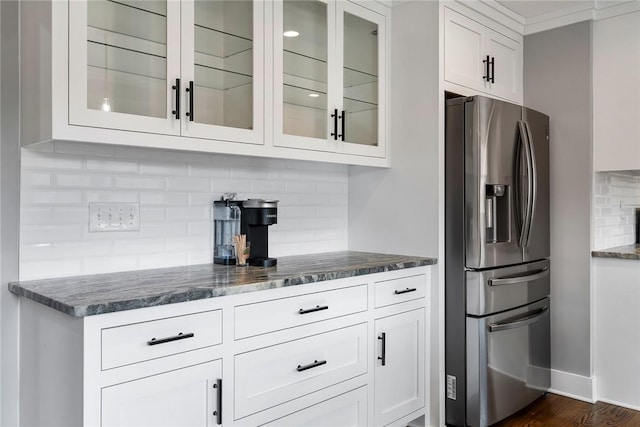 kitchen featuring decorative backsplash, stainless steel fridge, dark stone counters, dark hardwood / wood-style floors, and white cabinetry