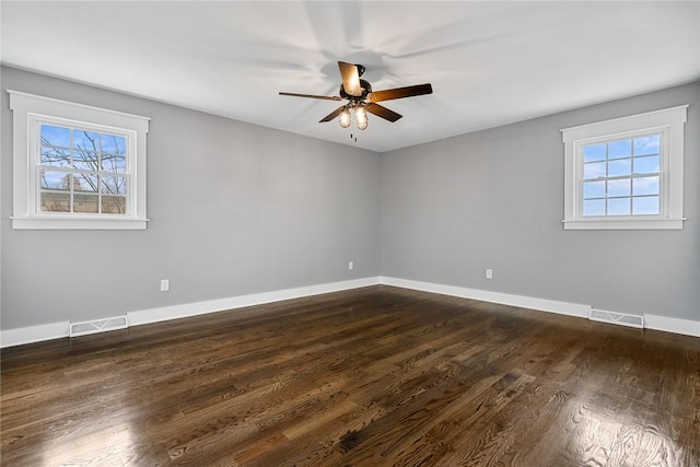 spare room featuring dark wood-type flooring, ceiling fan, and a healthy amount of sunlight