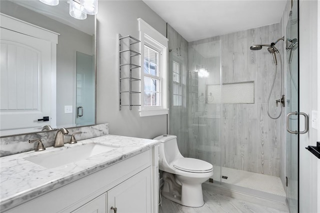 bathroom featuring hardwood / wood-style flooring, vanity, toilet, and a shower with door