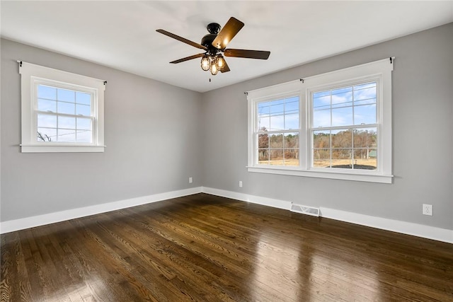 unfurnished room featuring a wealth of natural light, dark wood-type flooring, and ceiling fan