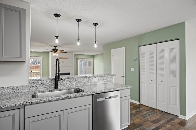 kitchen with ceiling fan, sink, stainless steel dishwasher, pendant lighting, and a textured ceiling