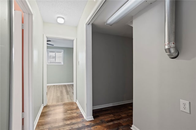 hallway with a textured ceiling and dark hardwood / wood-style floors