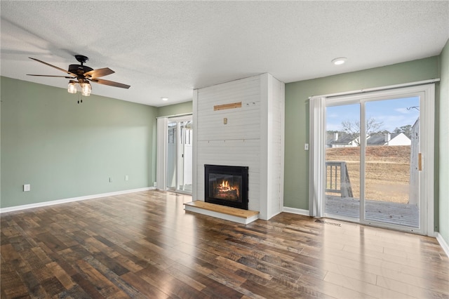 living room featuring dark hardwood / wood-style flooring, ceiling fan, a fireplace, and a textured ceiling