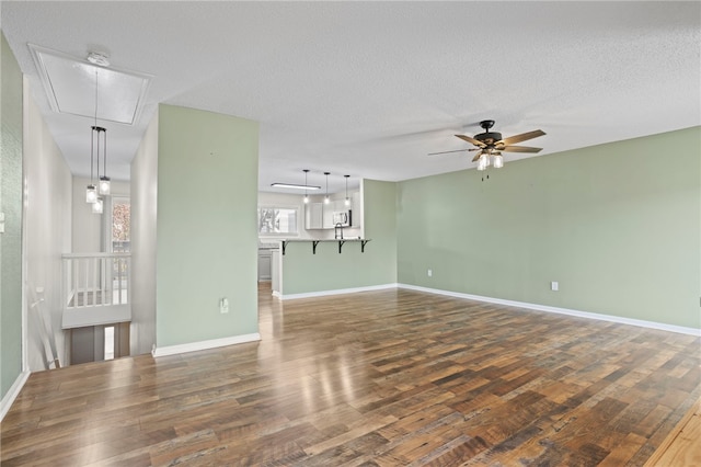 unfurnished living room featuring dark hardwood / wood-style floors, ceiling fan, and a textured ceiling