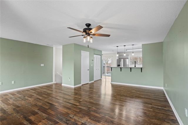 unfurnished living room with a textured ceiling, ceiling fan, sink, and dark hardwood / wood-style floors