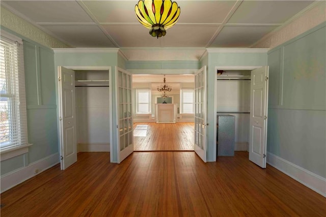 unfurnished bedroom with multiple windows, hardwood / wood-style floors, french doors, and a notable chandelier