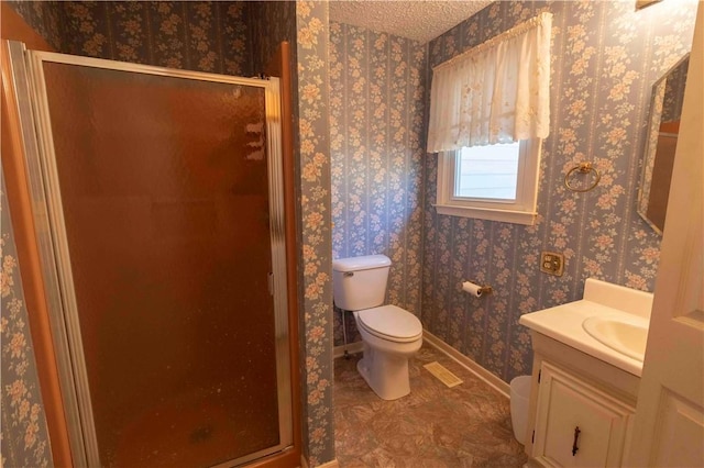 bathroom with a textured ceiling, vanity, toilet, and a shower with door